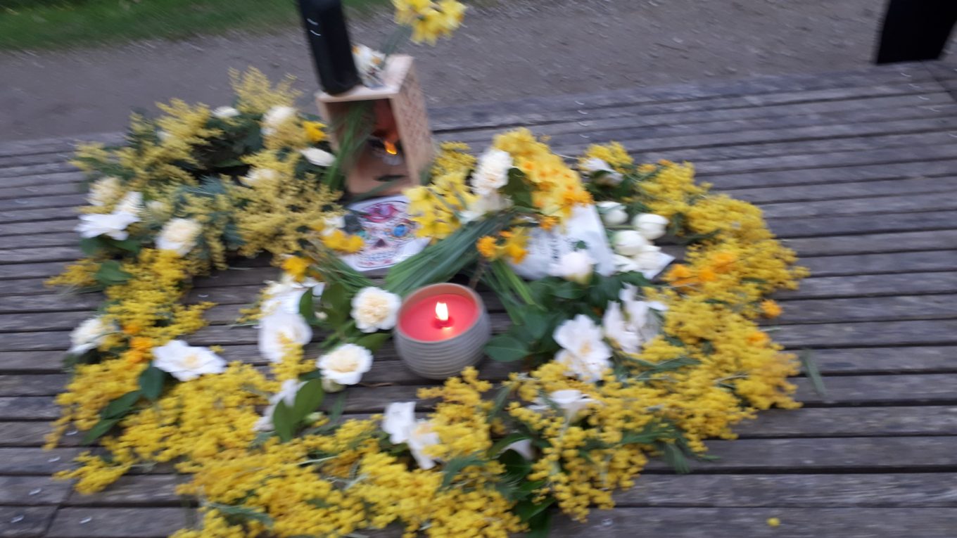 Photo de la composition florale réalisée en hommage à Antoine composée de mimosa et fleurs blanches et une bougie au milieu